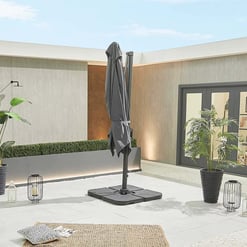 Modern outdoor patio with a large gray umbrella, potted plants, ambient lighting, and decorative lanterns, showcasing stylish home and garden outdoor living space.