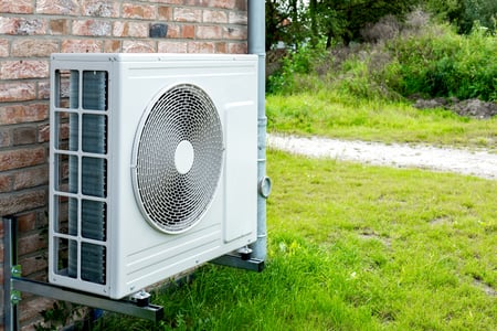 An air-sourced heat pump installed outside a suburban home.