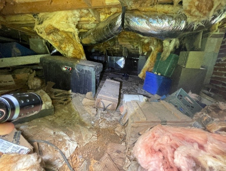 Unremediated crawl space with sagging fiberglass insulation, exposed soil, debris, and deteriorated moisture barriers.