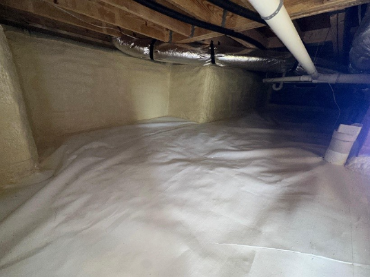 Encapsulated crawl space with closed-cell spray foam applied to foundation walls and a sealed vapor barrier covering the floor.
