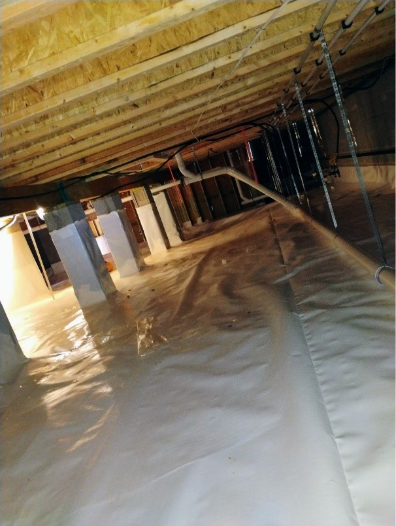 Crawl space floor and support piers covered with a reinforced white vapor barrier during encapsulation.