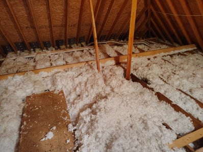 Traditional vented attic with blown-in fiberglass insulation on the attic floor before spray foam installation.
