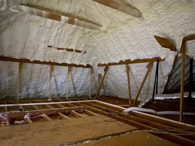 Completed open-cell spray foam attic with insulation installed along the roofline and gable walls.