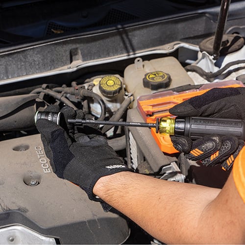 klein 65242 Flip-16 KNECT™ Ratcheting Impact Flip Socket Screwdriver Set with a person holding the screwdriver while working on a car
