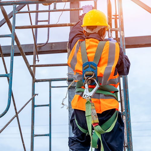 person climbing a ladder on a jobsite, wearing hard hat and fall protection