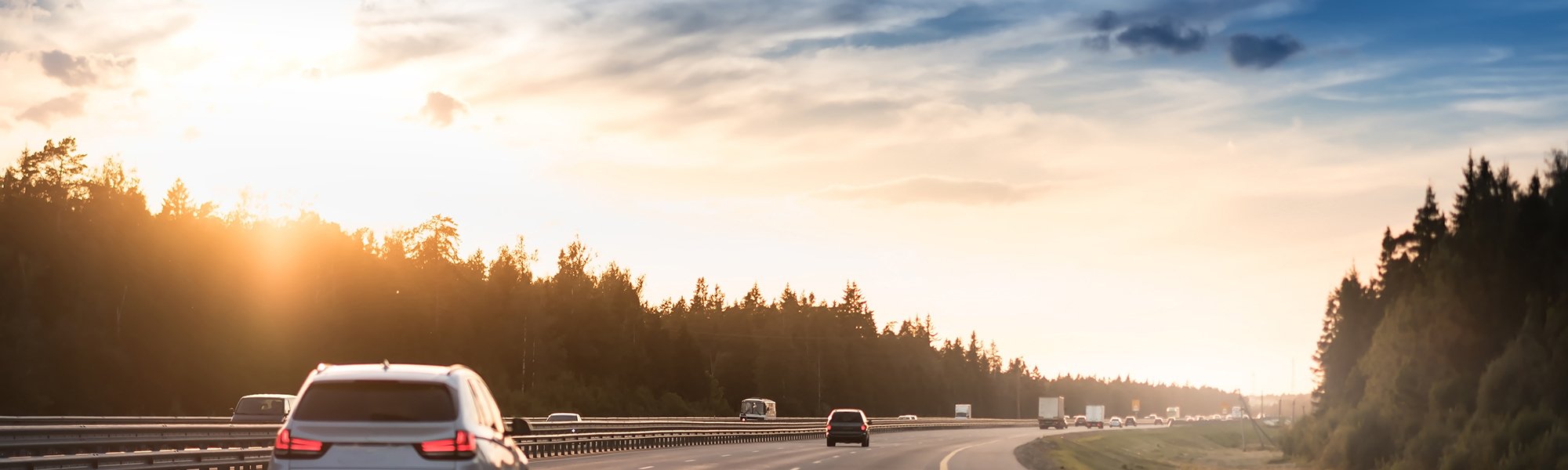 Highway traffic in sunset. Road with metal safety barrier or rail. cars on the asphalt under the cloudy sky