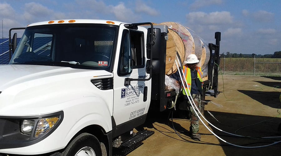 truck with wire on the flatbed and a man standing by the truck