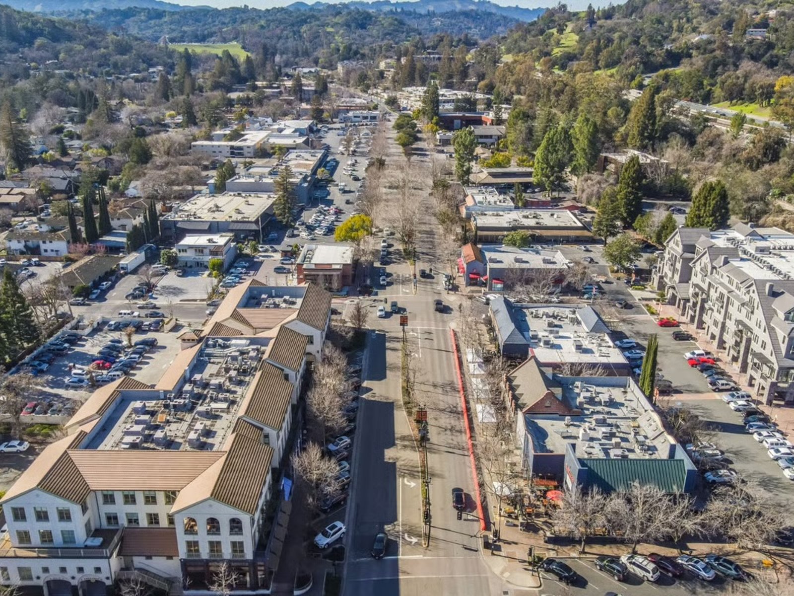 Aerial view of downtown Lafayette, California, showing streets, shops, businesses, and surrounding wooded hills.