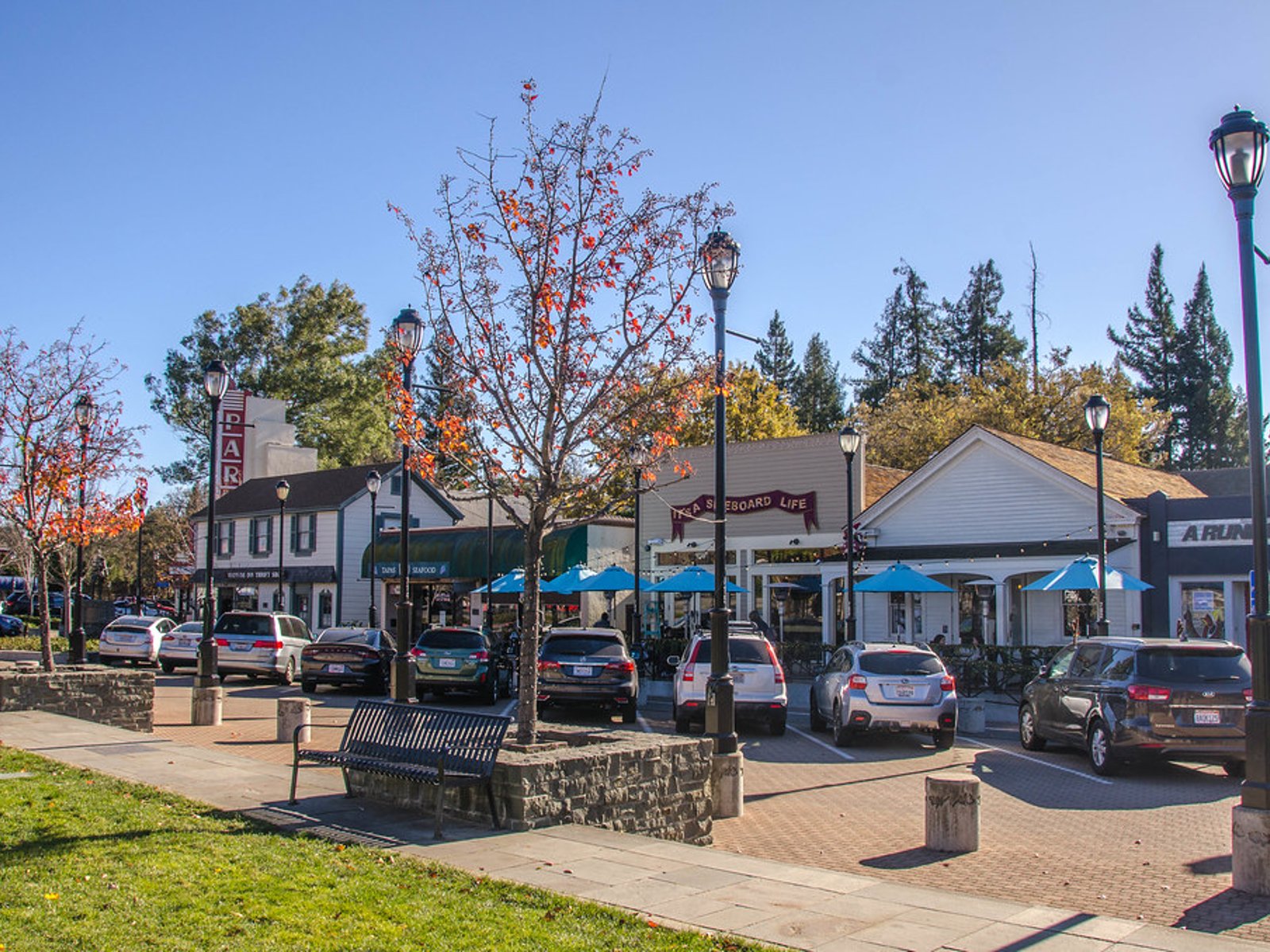 Shops, restaurants, parked cars, trees, and outdoor seating along a downtown street in Lafayette, California.