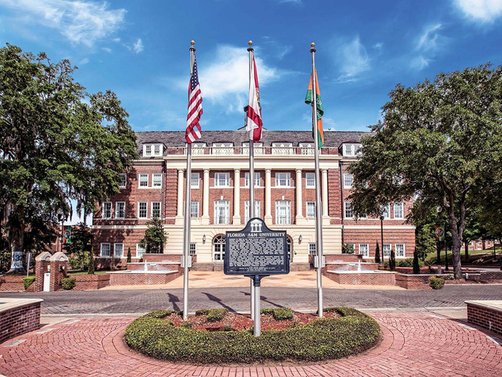 Lee Hall at Florida A&M University behind three flagpoles, a historic marker and brick walkways.