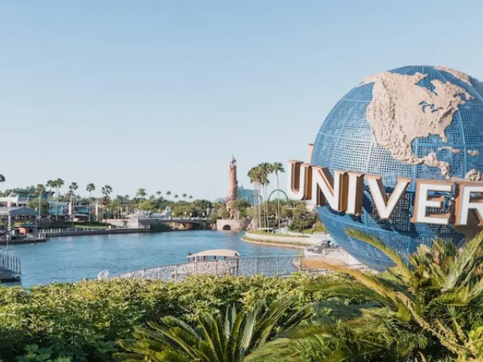 Universal Orlando Resort globe beside the lagoon, surrounded by palm trees and entertainment areas in Orlando, Florida.