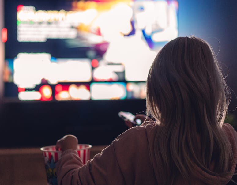 Photo of a person watching a streaming service and eating popcorn