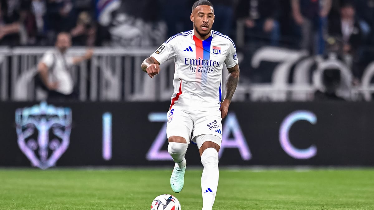 Corentin Tolisso in an Olympique Lyon white home shirt dribbling the ball during a match