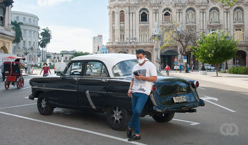 Joven, almendrón, Habana Vieja, Parque Central, taxi privado, tecnología. Foto: Ernesto Verdecia.