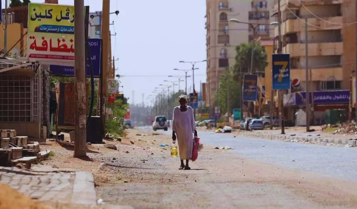 Un hombre atrapado por los combates en abril de 2023 camina hacia su casa en Jartum. Los habitantes de la devastada capital pasan mucha hambre mientras la guerra se prolonga hacia su segundo año. Foto: Fazi Abubakr/TNH