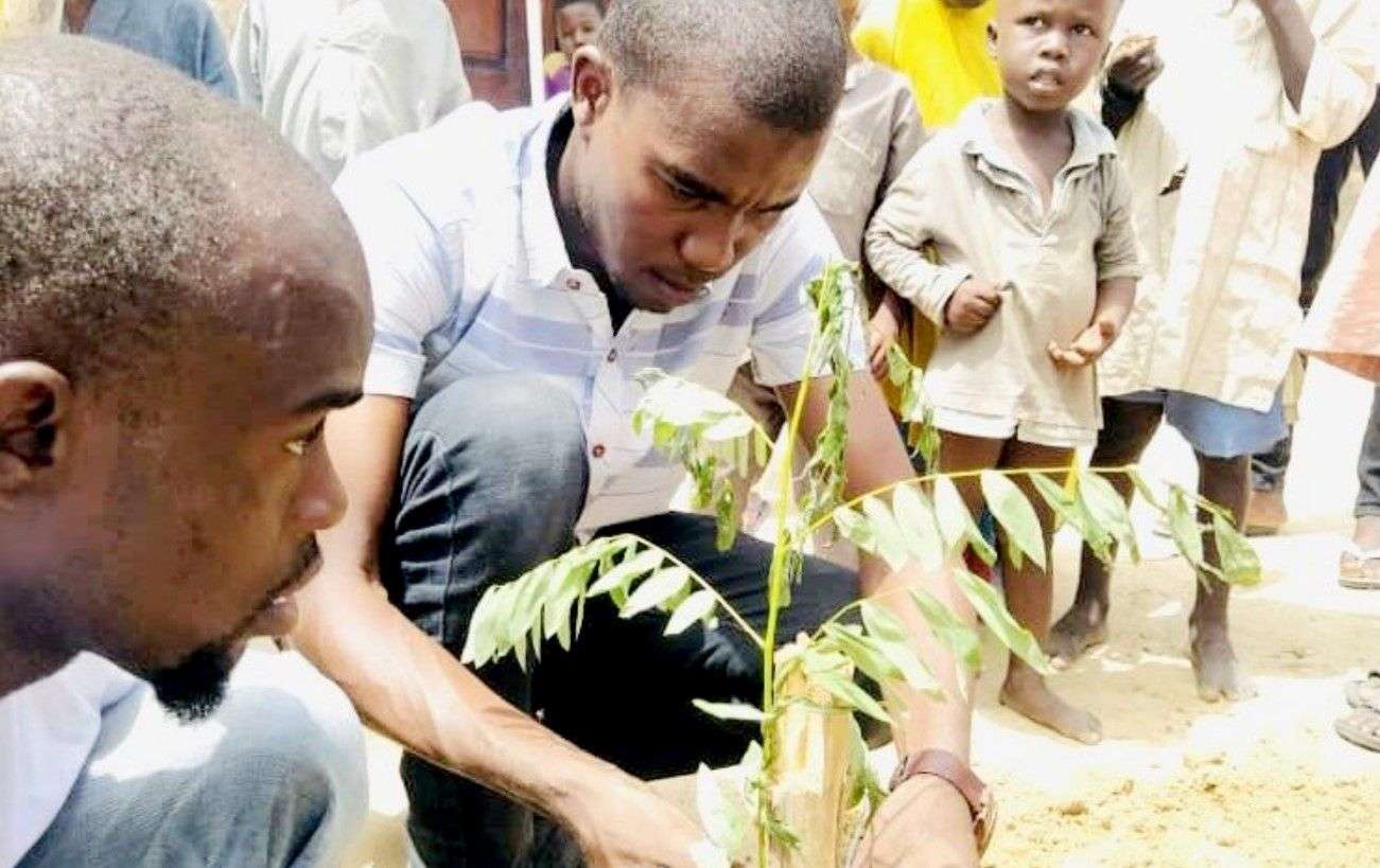 Ali Yerima tratando de ajustar y regar un árbol recién plantado en el área de Gomboru Liberty, Estado de Borno. Foto: Rukaiya Ahmed Alibe/HumAngle.