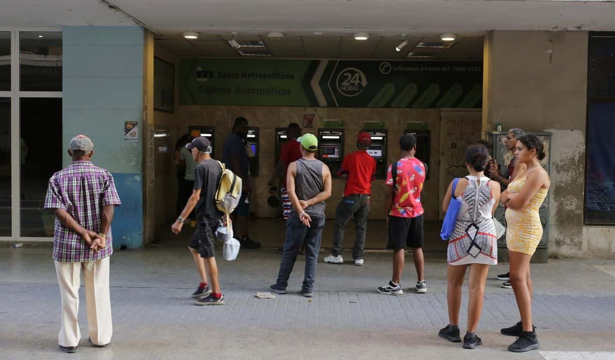 Varias personas esperan en el exterior de un banco con la esperanza de poder retirar pesos cubanos de un cajero automático, en La Habana, Cuba, el 22 de abril de 2024 (AP Foto/Ariel Ley).