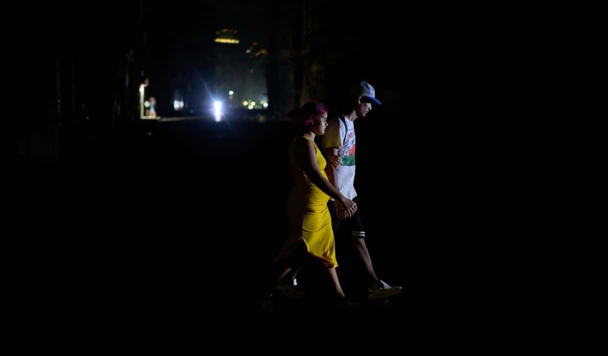 Dos personas cruzan una calle durante un apagón el 4 de marzo de 2026, en La Habana. (AP foto/Ramón Espinosa)