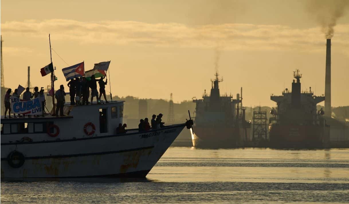Activistas ondean banderas cubanas y palestinas desde el buque Maguro, que llega procedente de México con ayuda humanitaria como parte del convoy "Nuestra América", en la bahía de La Habana, Cuba, el martes 24 de marzo de 2026. (AP Foto/Ramón Espinosa)