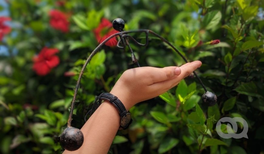 Mano sosteniendo adorno en jardín de marpacíficos, fondo verde, Cuba. Foto: Jorge Ricardo.