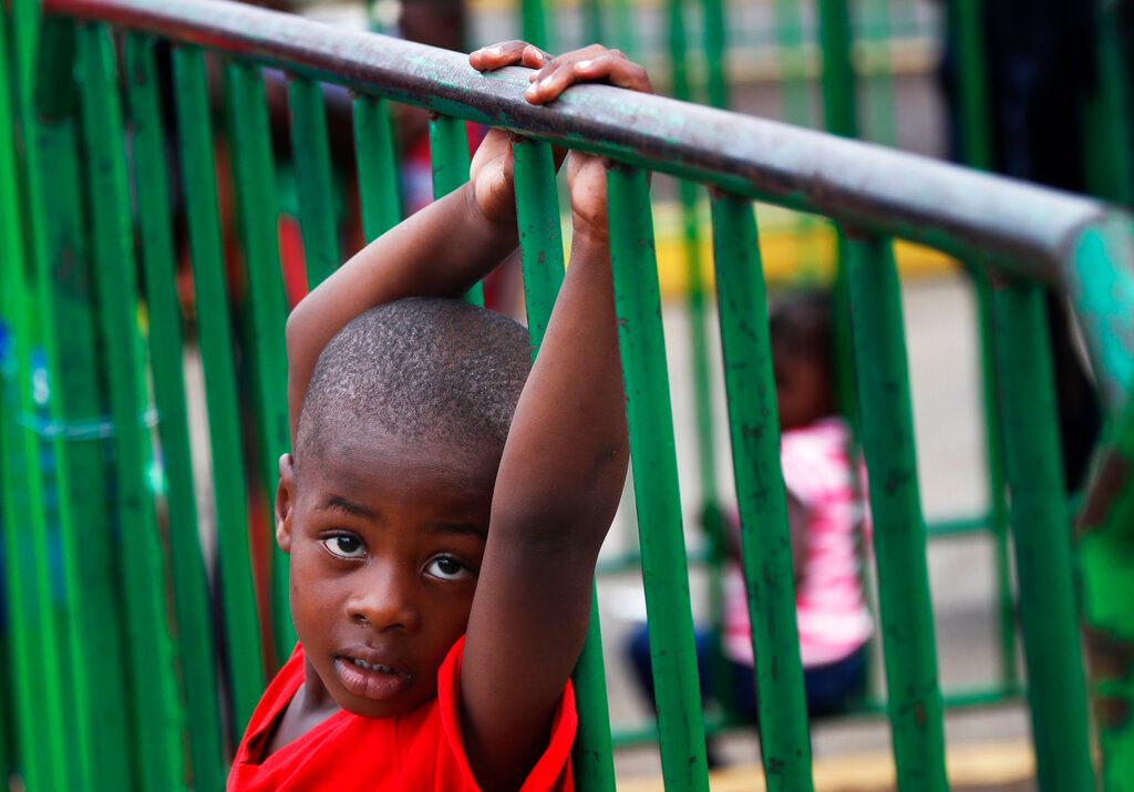 Un niño haitiano agarra una barrera en un centro de detención migratorio donde migrantes han acampado por semanas esperando respuesta a sus solicitudes de asilo en Tapachula, México, el miércoles 29 de mayo de 2019. (AP Foto/Marco Ugarte)