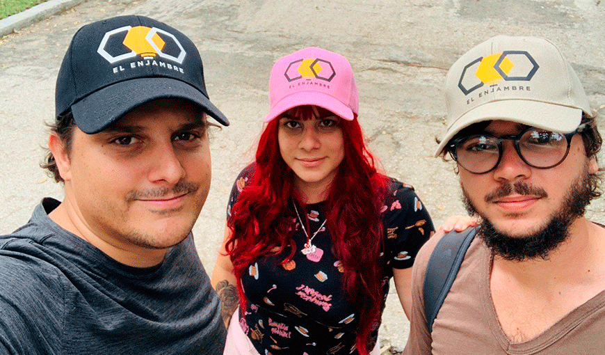 Camilo Condis, Lucía March y Miguel Alejandro Hayes lucen gorras con el logotipo de El Enjambre.