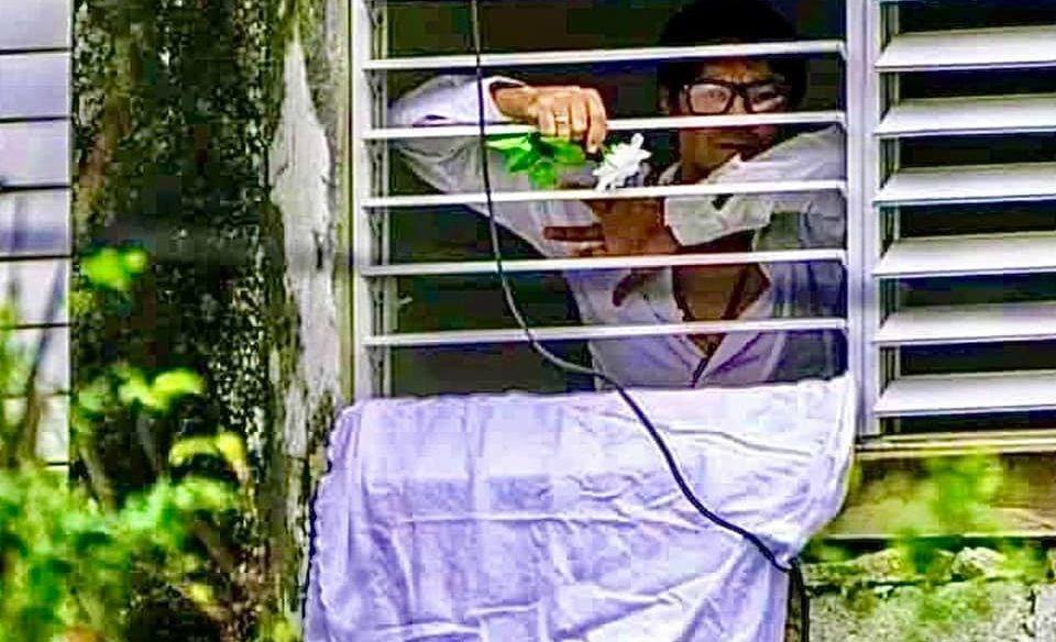 Yunior García Aguilera sostiene una flor blanca desde la ventana de su apartamento en La Habana / Foto: AFP