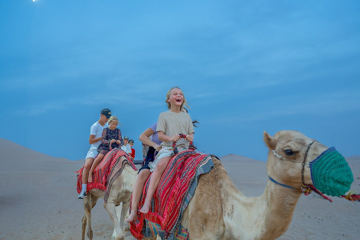 Camel safari ride through Abu Dhabi’s Al Khatim desert as part of evening safari itinerary with panoramic dune views