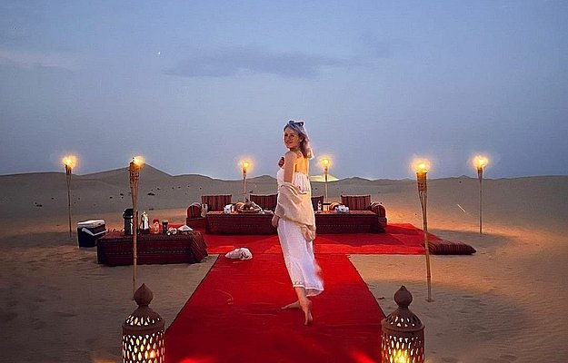Romantic private dune dinner in Abu Dhabi with candlelight setup, luxury seating, and exclusive desert ambiance