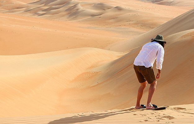 Guest sandboarding on Abu Dhabi desert dunes during evening safari