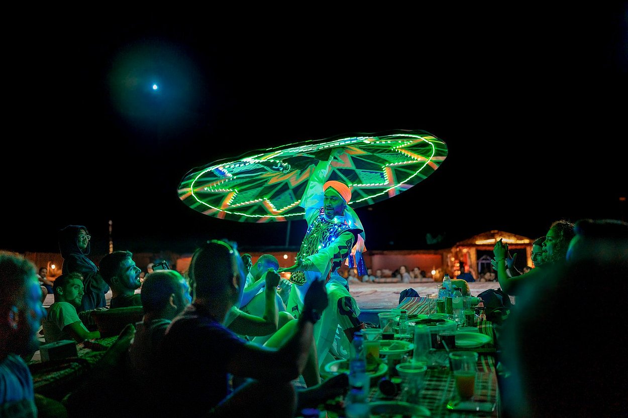 Vibrant Tanoura dance performance by traditional artists at Abu Dhabi desert camp during cultural evening desert safari show