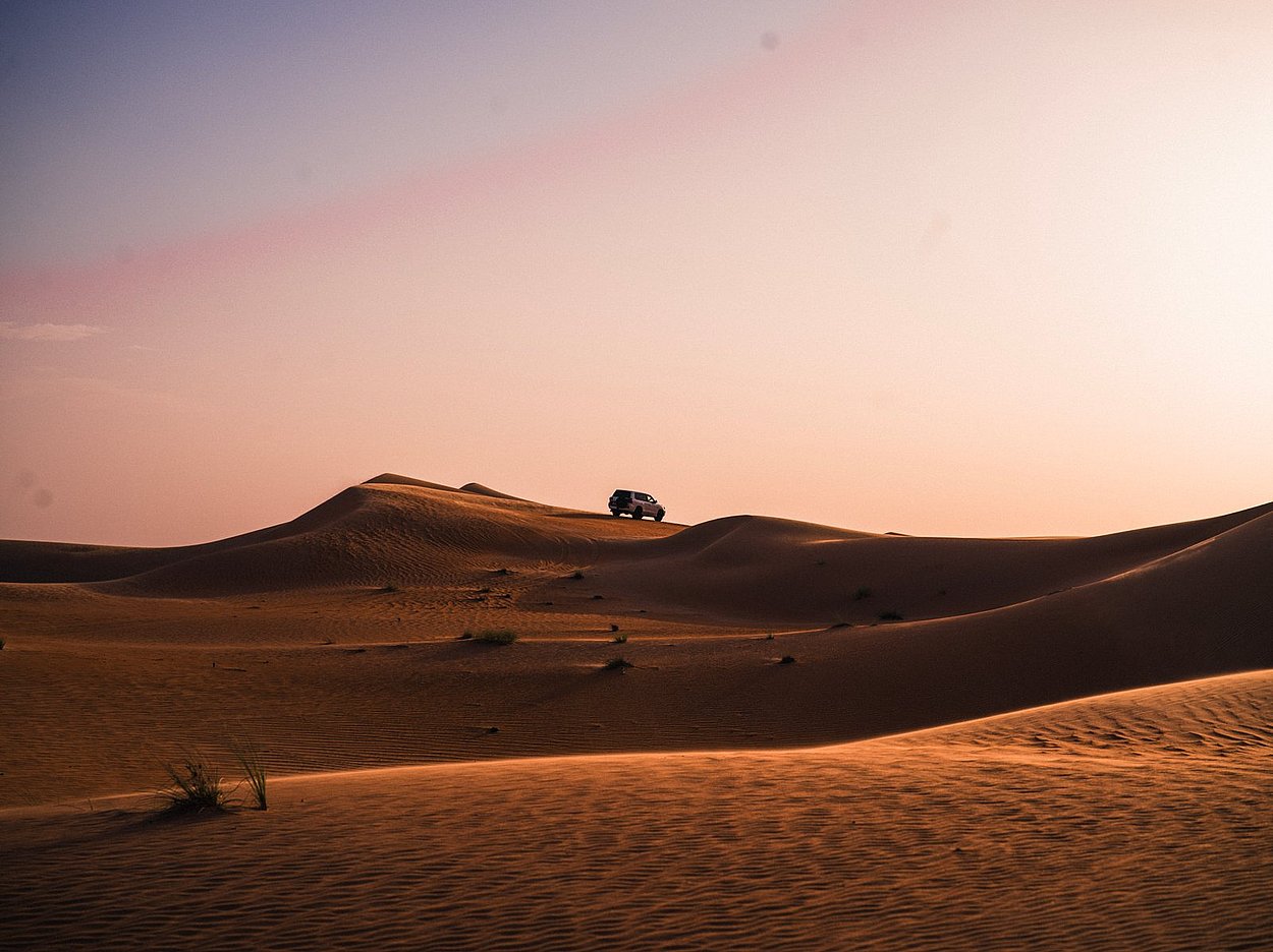 4x4 vehicle crossing golden dunes at Al Quaa desert during sunset safari in Abu Dhabi