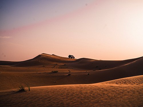 4x4 vehicle crossing golden dunes at Al Quaa desert during sunset safari in Abu Dhabi