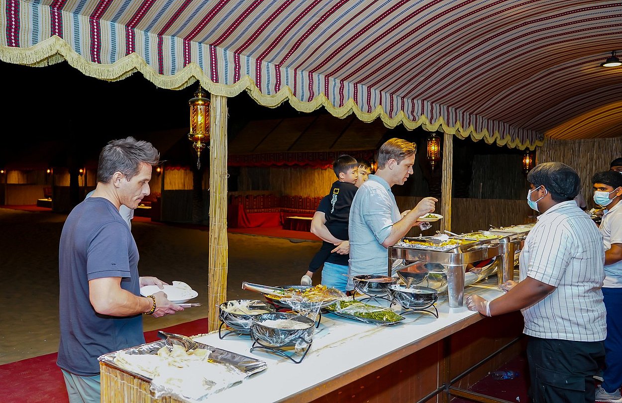 Guests selecting dishes from the desert camp buffet