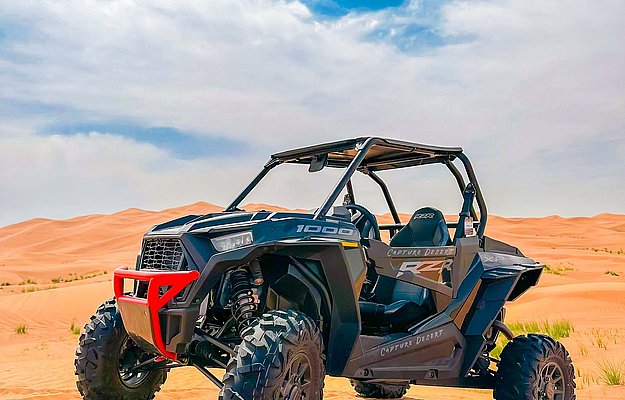 Desert buggy parked on golden sand under blue Abu Dhabi sky