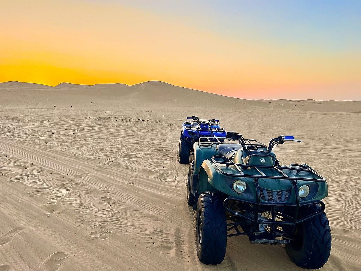 Riders preparing quad bikes for a guided off-road desert tour in Abu Dhabi