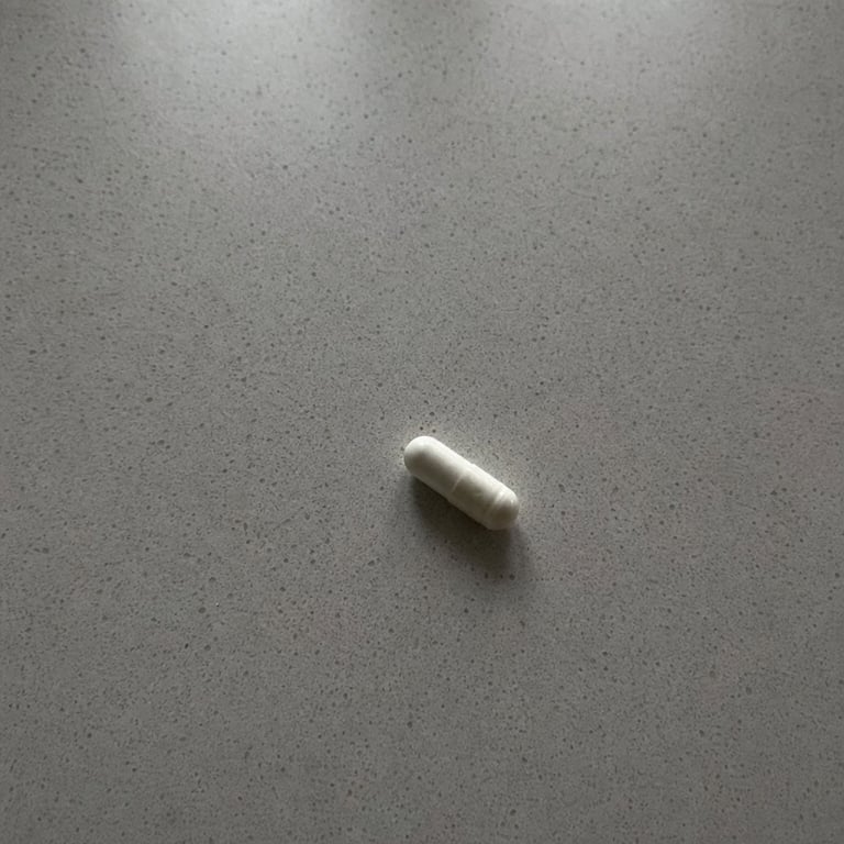 A single probiotic capsule held up against a plain background
