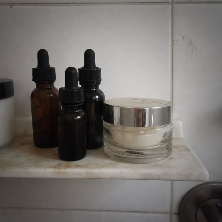 A few dark-spot serum bottles and a pricey cream jar on a bathroom shelf