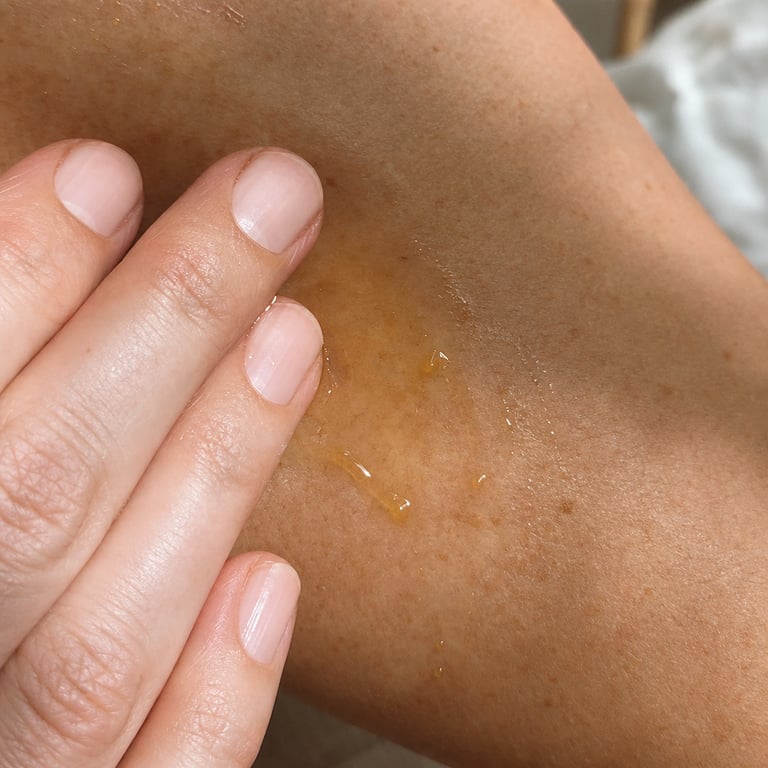 Close-up of golden oil drops being smoothed into the skin of a mature upper arm