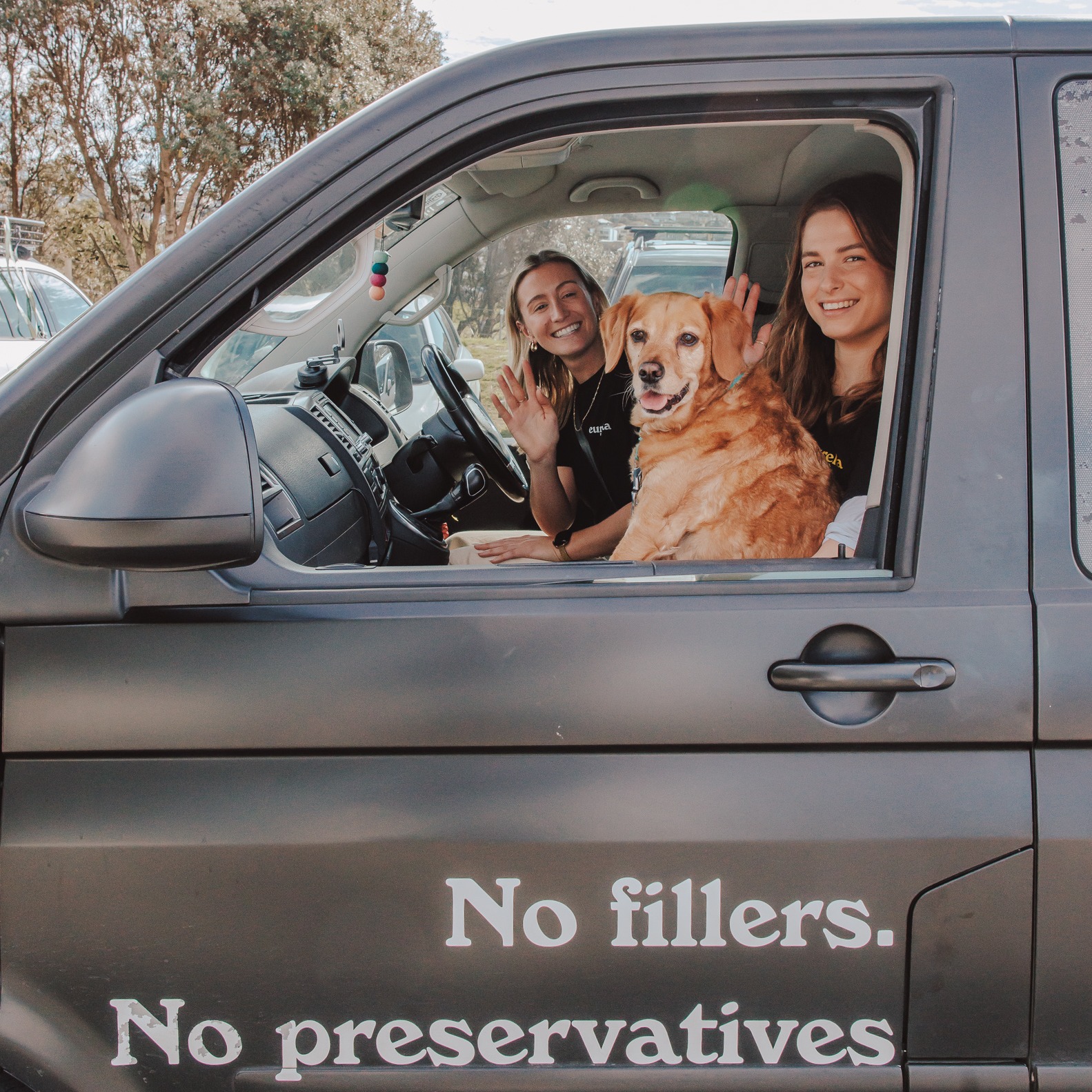 Two Eureka team members and a golden retriever waving from the Eureka van, No fillers No preservatives painted on the door