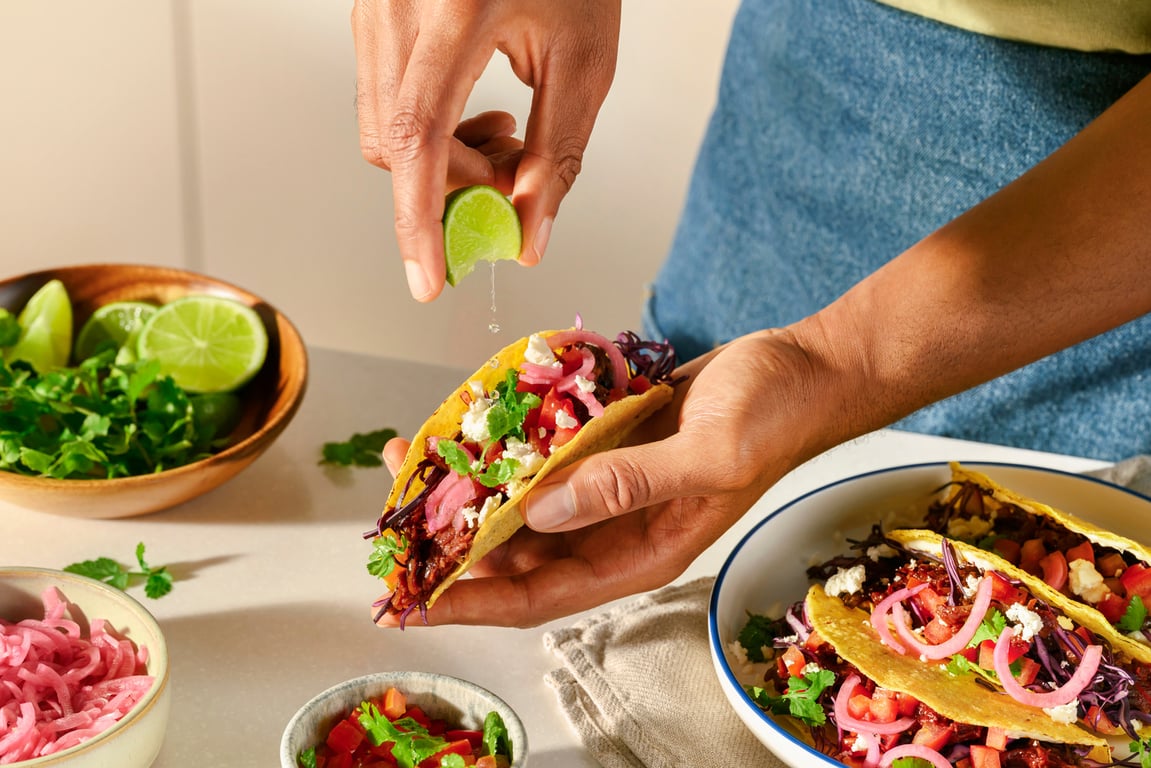Hands assembling fresh tacos on a kitchen counter