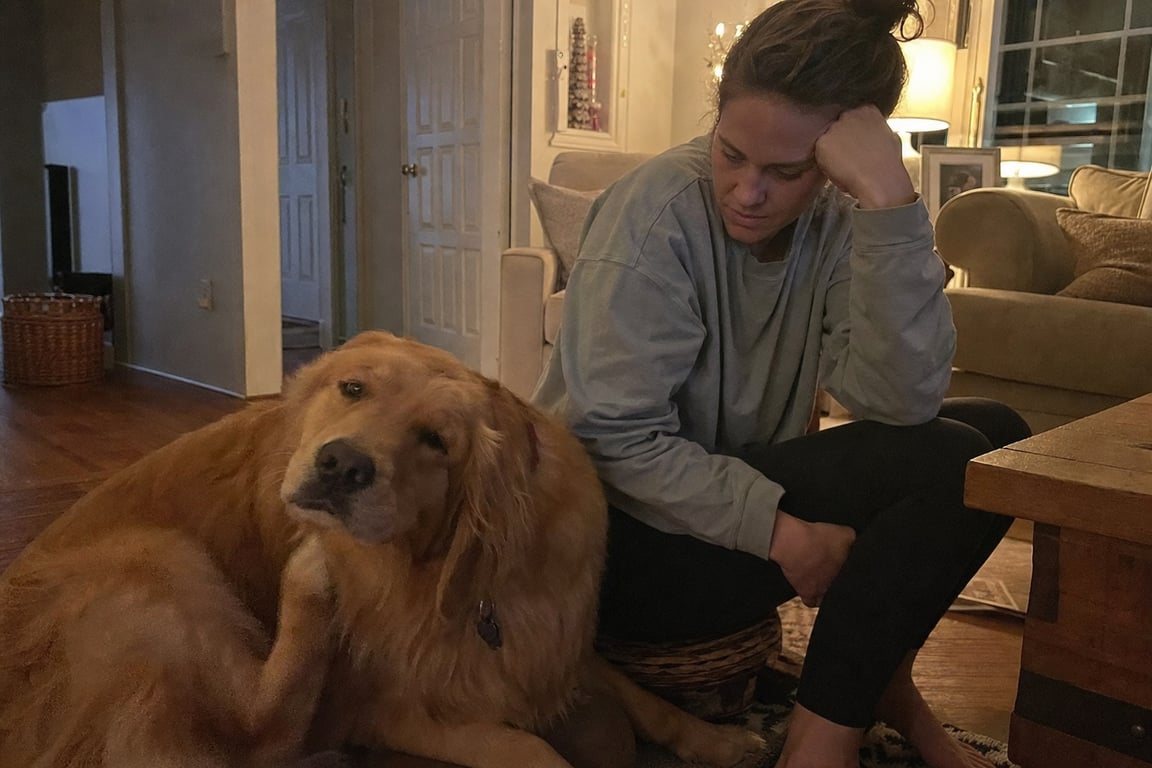 Woman sitting on floor with her golden retriever late at night, dog scratching