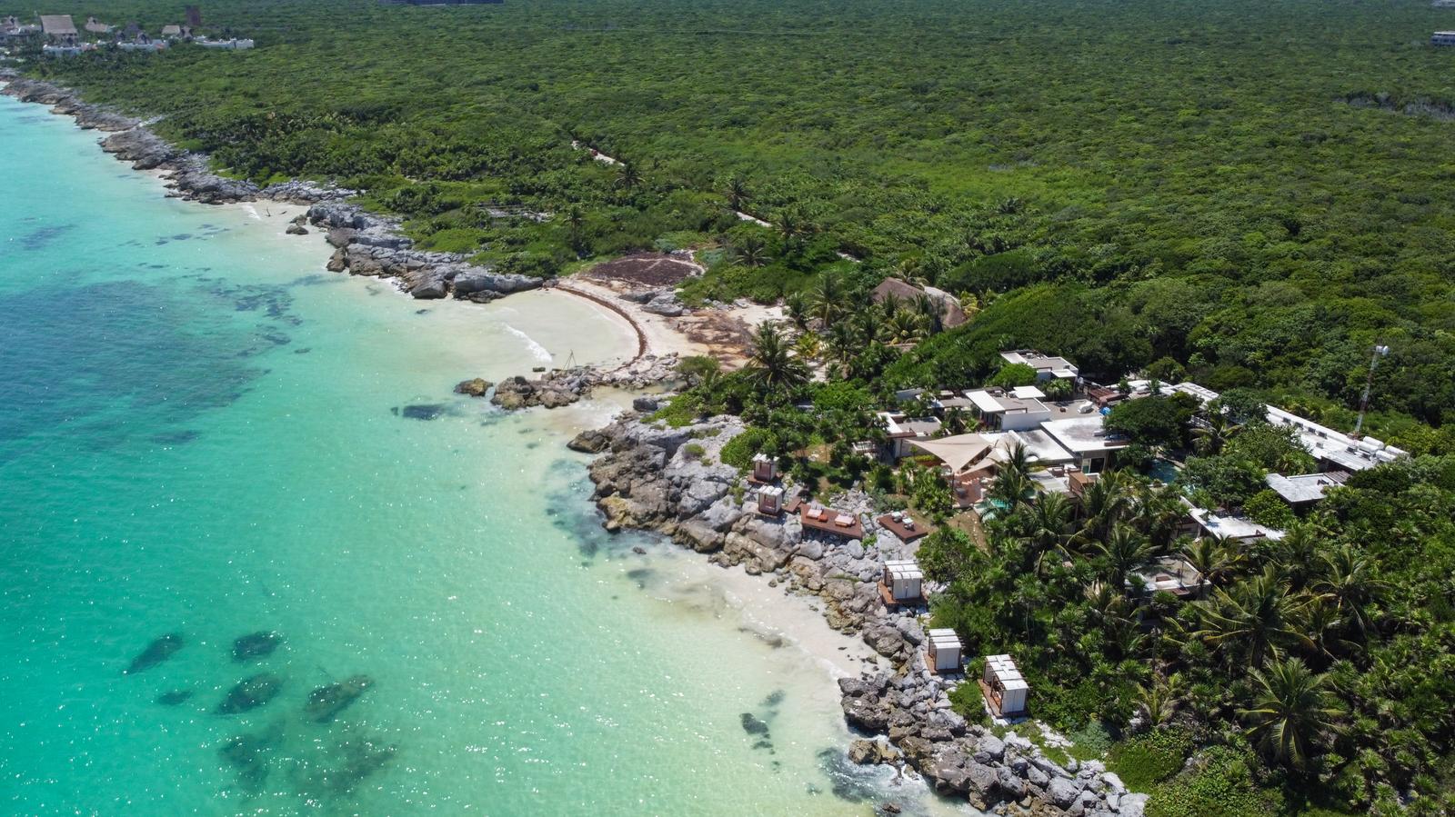 Aerial view of Mi Amor nestled on a rocky Tulum coastline with turquoise water and dense jungle vegetation