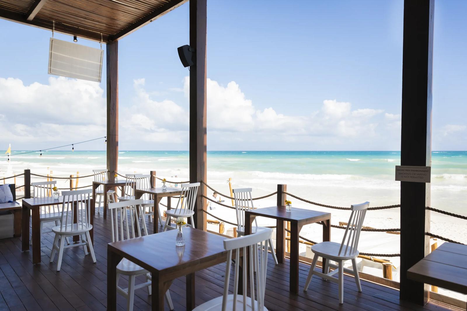 La Zebra Mediterranean's beachfront terrace with dining tables overlooking turquoise Caribbean waters and white sand beach
