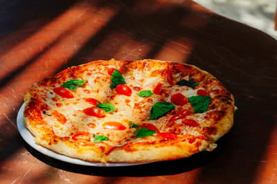 Margherita pizza with tomatoes and basil on a plate at Tulumania, warmly lit and inviting.