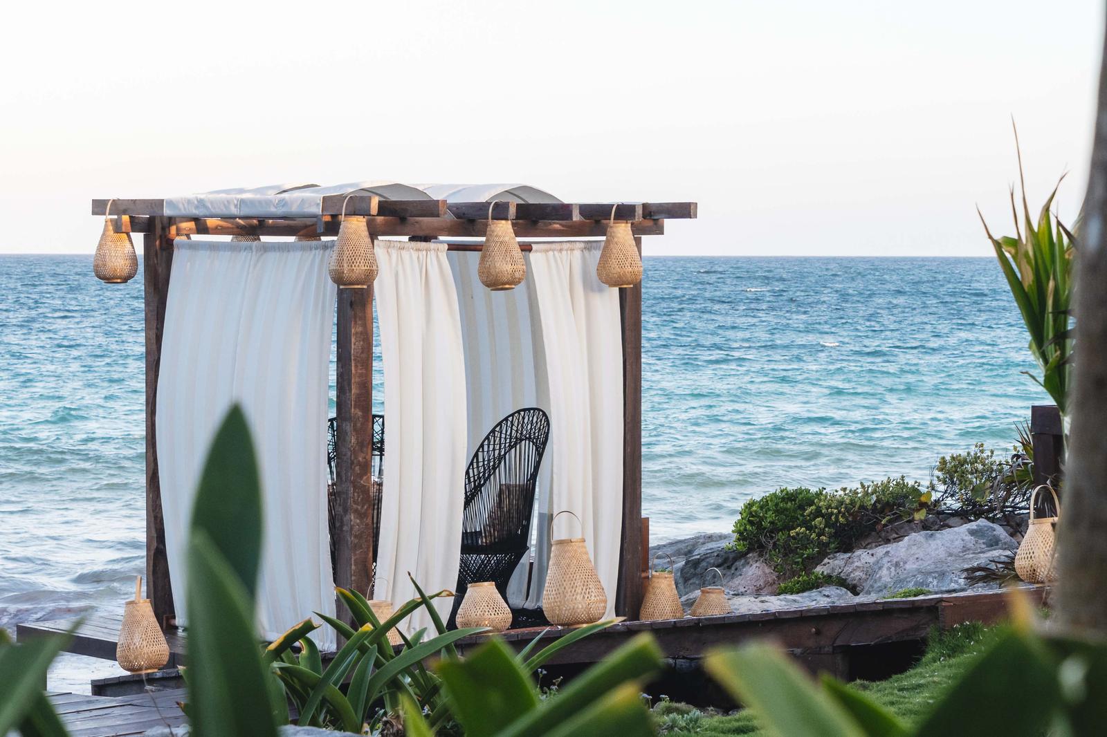 Mi Amor's beachfront cabana with white curtains and woven pendant lights overlooking the Caribbean Sea.
