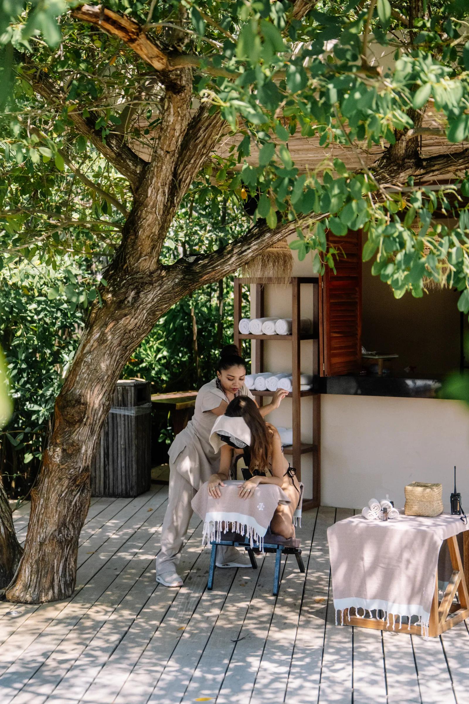 A masseuse performs a head massage on a guest sitting in a massage chair on Atta's