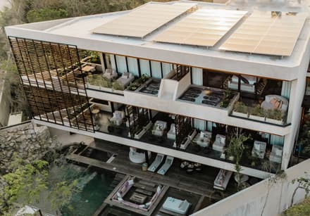 Casa Luna villa viewed from above, with terraces, rooftop solar panels, and a pool amid peaceful Tulum greenery.