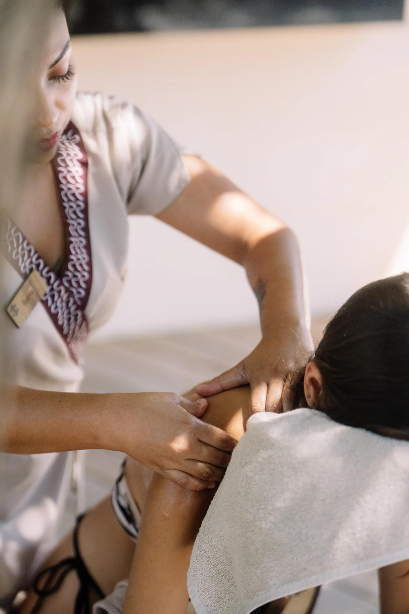 A therapist massages a woman's shoulders during a spa treatment at Atta / Tuuch.