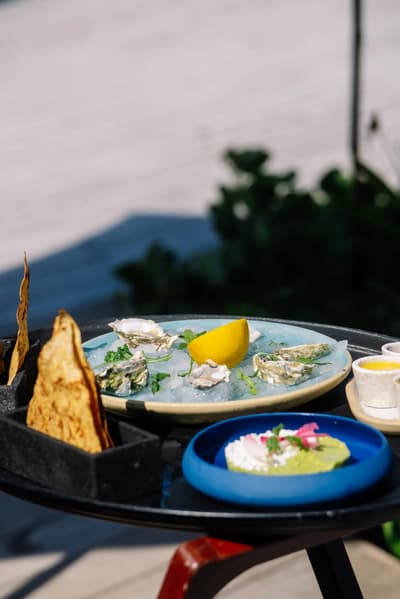 Fresh oysters on ice and flatbread sit on a tray on Atta's sunny outdoor terrace